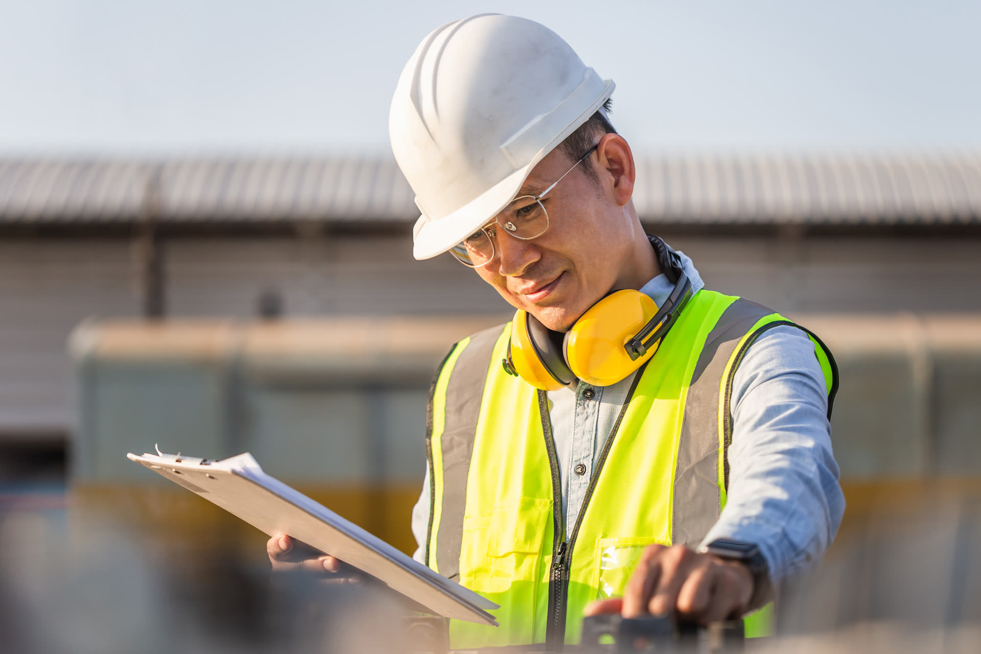 An engineer reviewing a clipboard at an industrial site